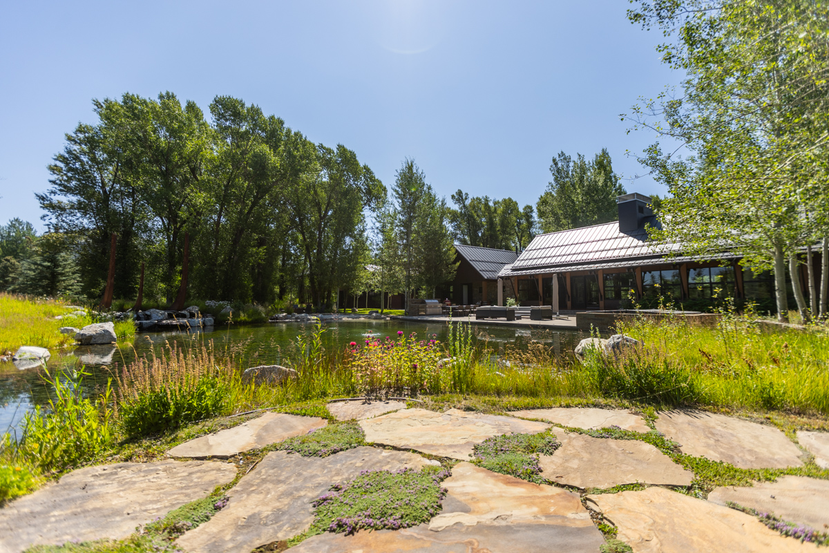 flagstone patio area pond native wild area trees house
